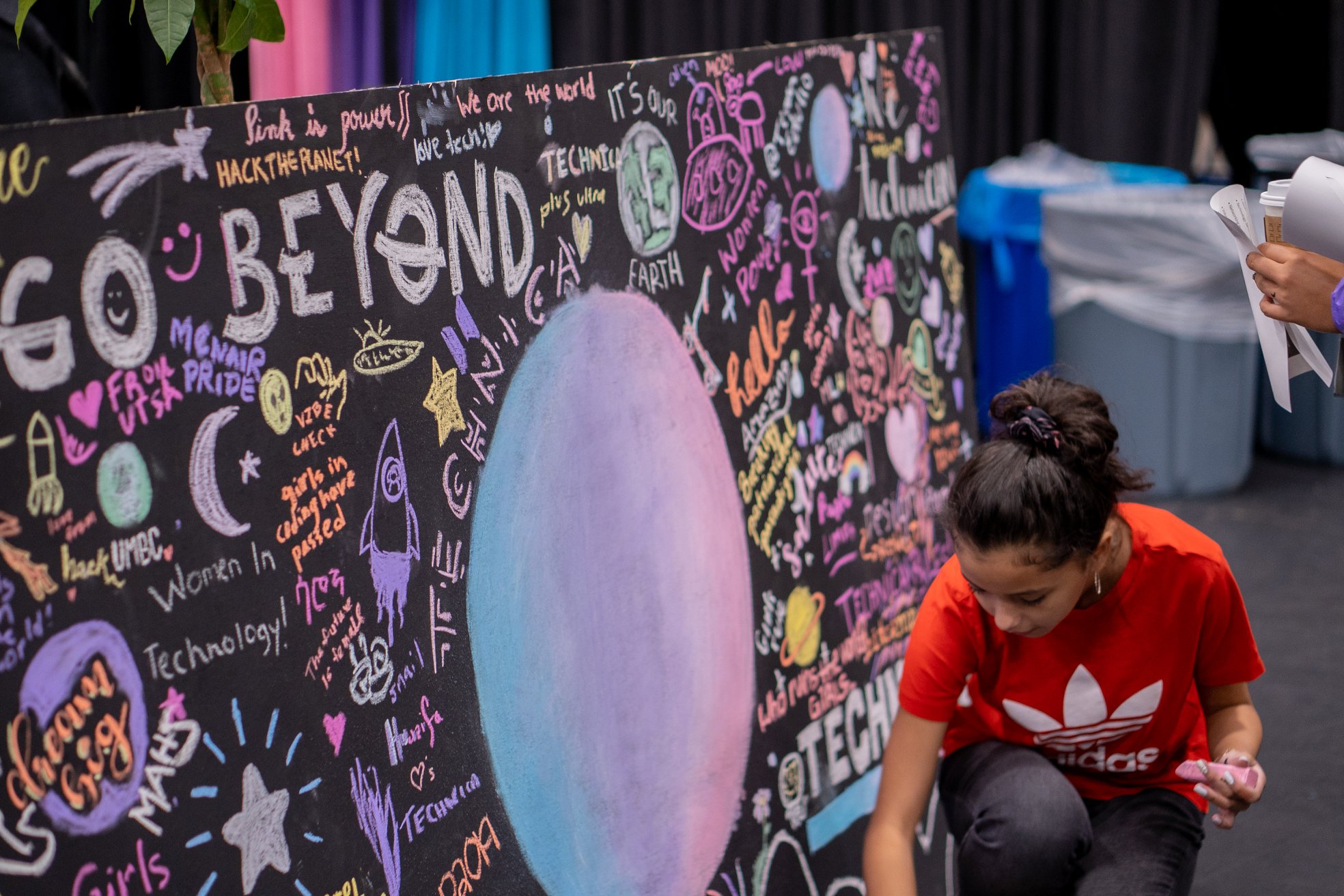 Technica 2019 Go Beyond: A Technica Hacker drawing on colorful chalk mural.
